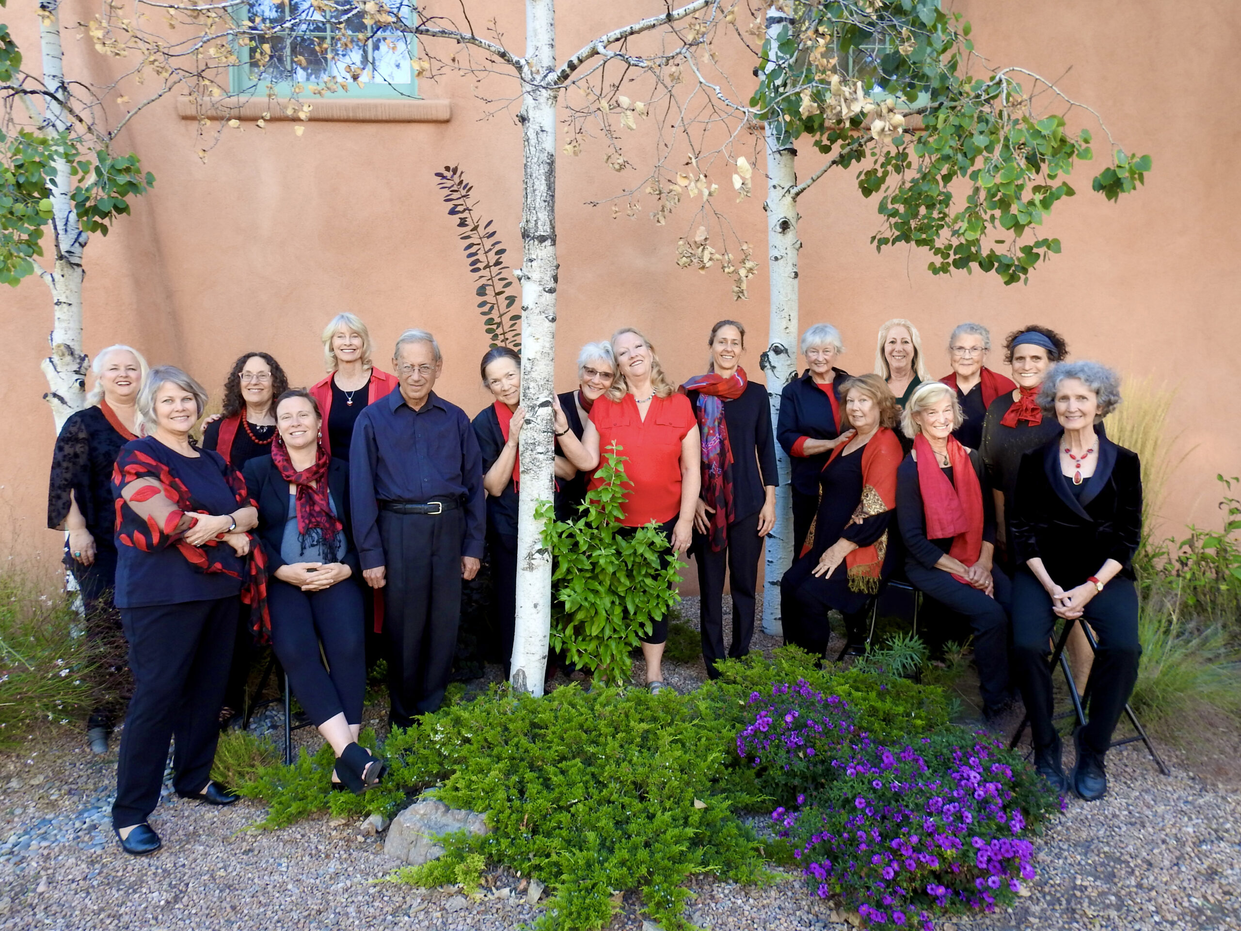 Ensemble members, wearing black with red scarves, standing amongst aspens 