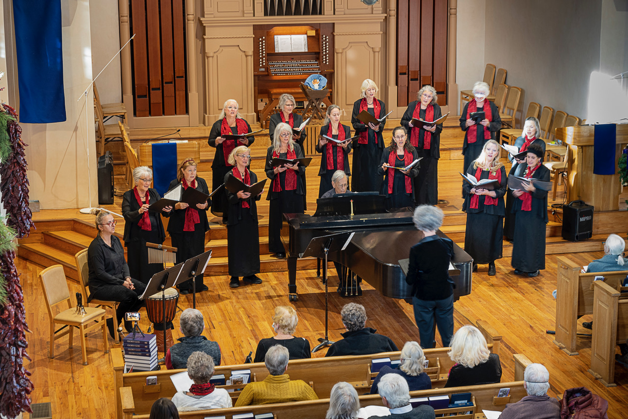 Singers on stage, wearing black with red scarves, photo from balcony