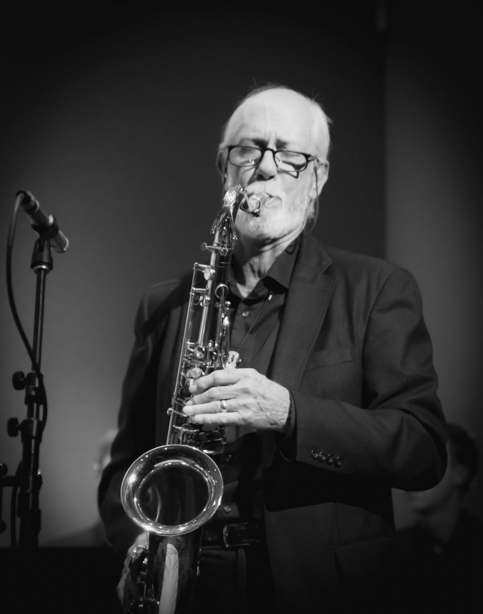 black and white photo of man playing saxophone, eyes closed in concentration