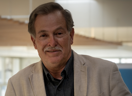 Z. Randall Stroope - photo Man with wry smile, wearing light tan sport coat and navy collared shirt. Background is blurred.