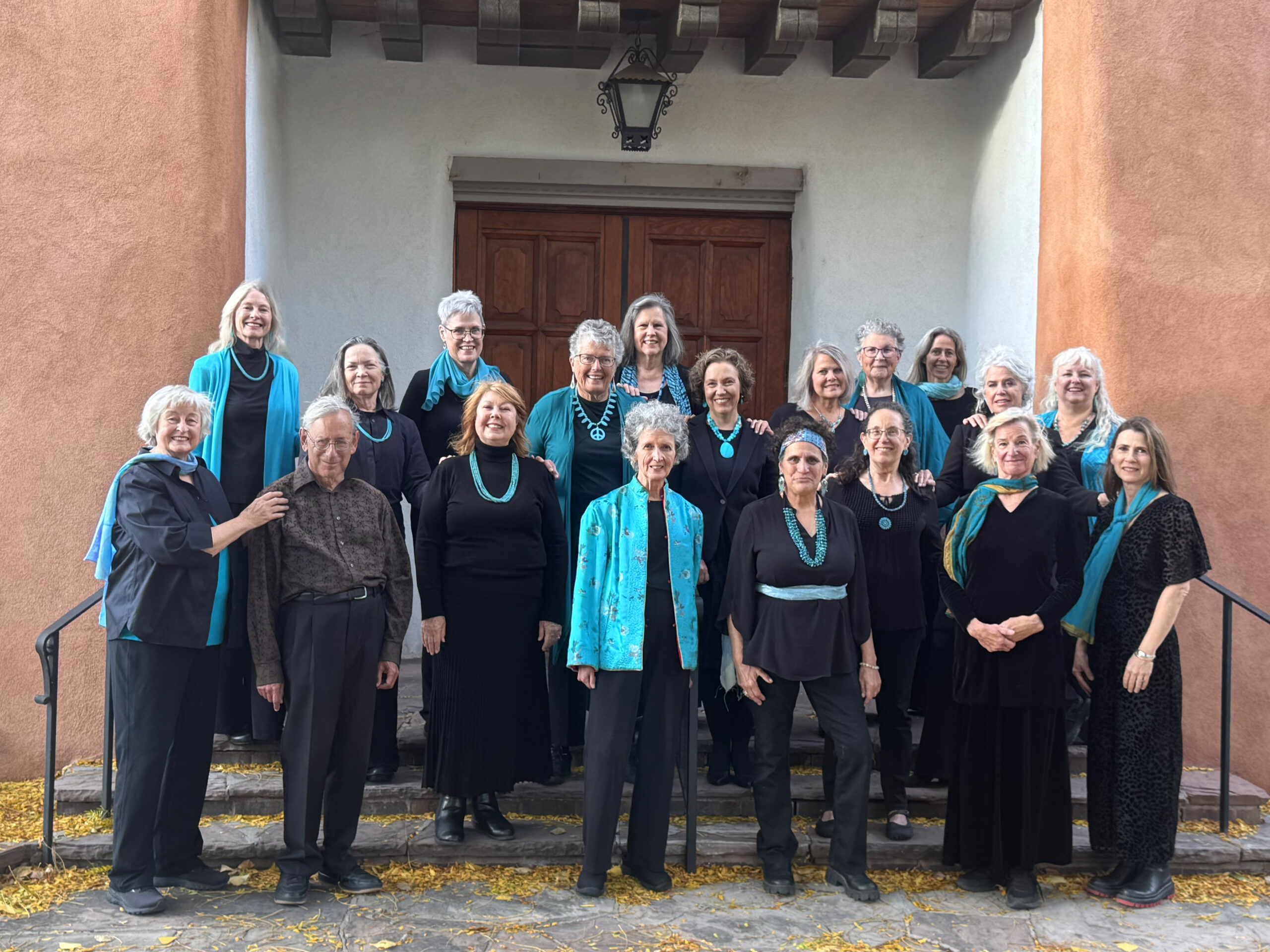 2025 group of 18 women and one man, wearing black and turquoise, standing on church steps